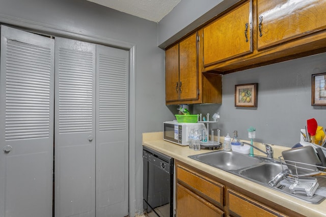 kitchen with sink, black dishwasher, and a textured ceiling