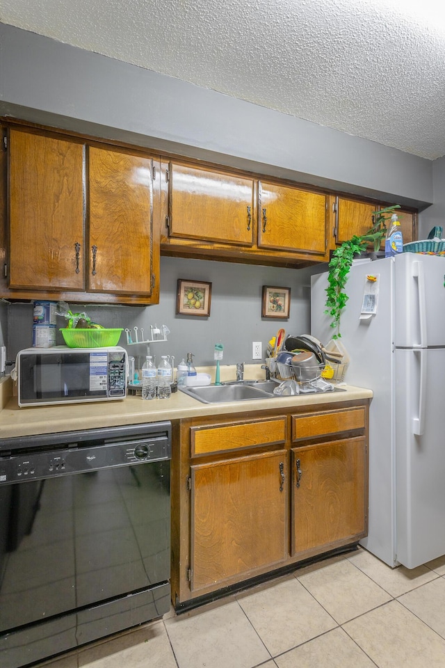 kitchen with light tile patterned floors, white refrigerator, black dishwasher, and a textured ceiling