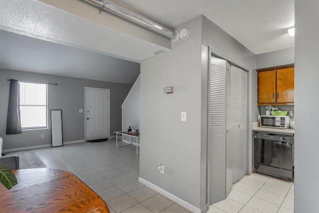 kitchen with light tile patterned floors, dishwasher, and a textured ceiling