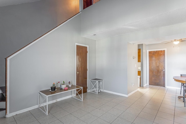 spare room featuring ceiling fan, light tile patterned flooring, and a towering ceiling