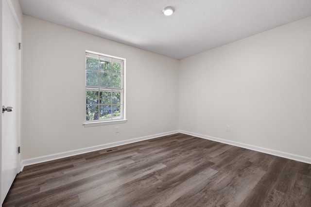 spare room featuring dark wood-type flooring and a textured ceiling