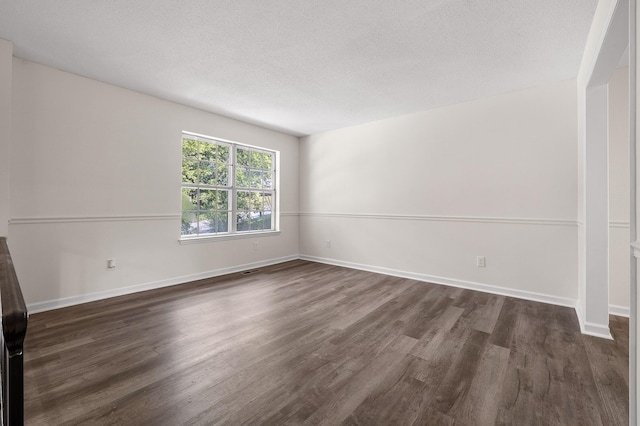 empty room featuring a textured ceiling and dark hardwood / wood-style floors