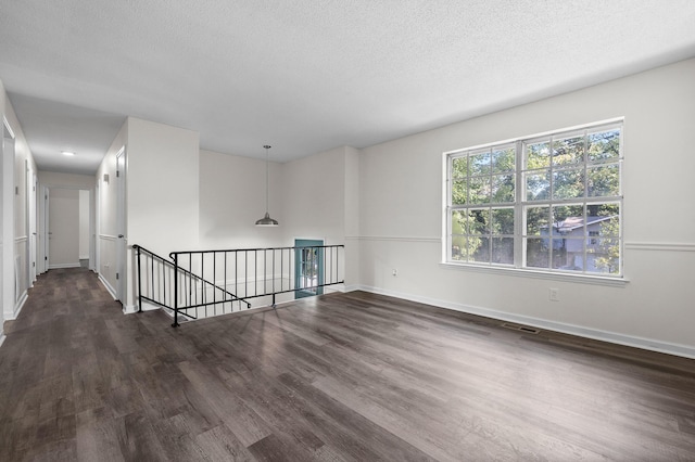 empty room featuring a textured ceiling and dark hardwood / wood-style floors