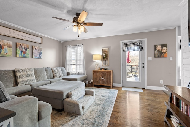 living area featuring crown molding, ceiling fan, wood finished floors, and baseboards