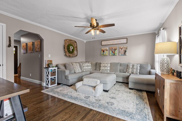 living area with arched walkways, wood finished floors, a ceiling fan, ornamental molding, and baseboards