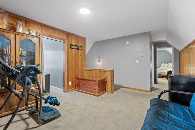 workout room with light carpet, baseboards, wooden walls, and vaulted ceiling