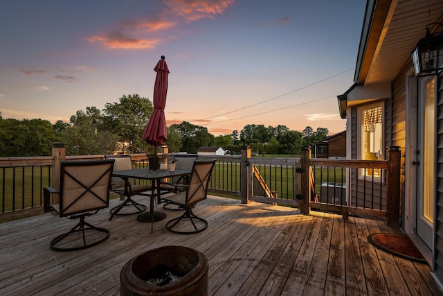 deck at dusk featuring a lawn and outdoor dining area