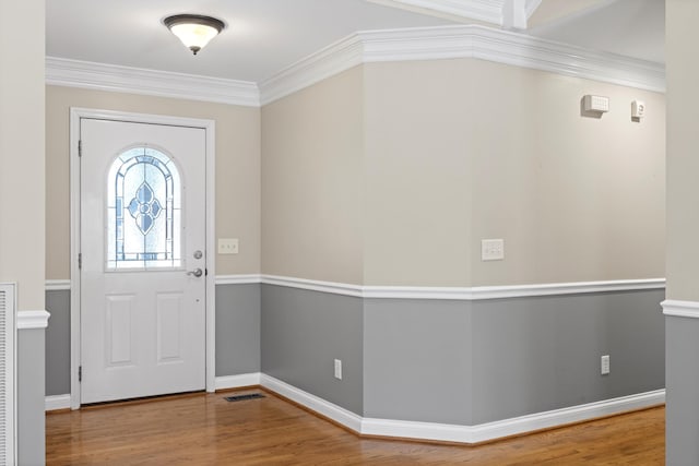 foyer with wood-type flooring and crown molding