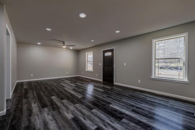 empty room featuring dark wood-style floors, baseboards, and ceiling fan