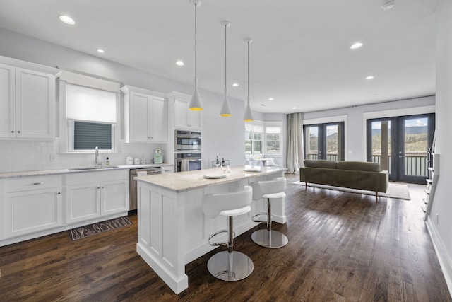 kitchen featuring french doors, sink, a center island, backsplash, and white cabinets