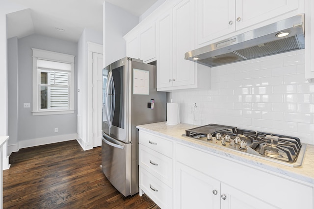 kitchen featuring appliances with stainless steel finishes, white cabinetry, dark hardwood / wood-style floors, light stone countertops, and decorative backsplash