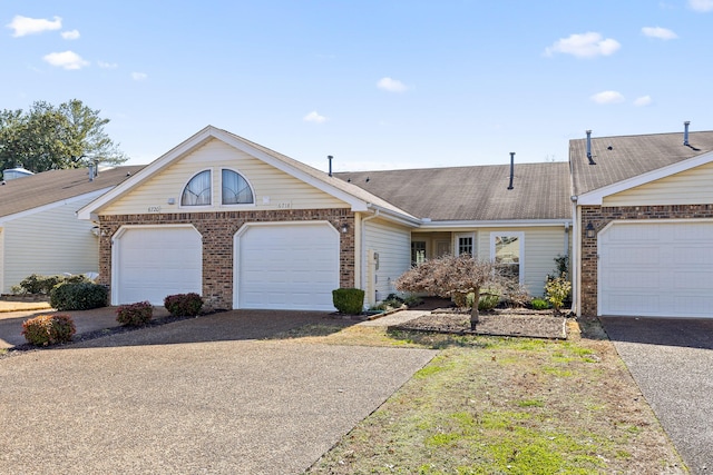 view of front of home featuring a garage, brick siding, driveway, and roof with shingles