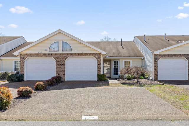 townhome / multi-family property featuring a garage, brick siding, and driveway