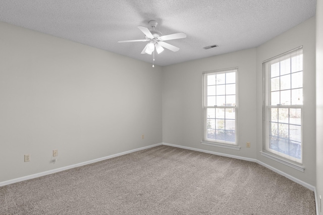 carpeted spare room featuring ceiling fan, a textured ceiling, visible vents, and baseboards