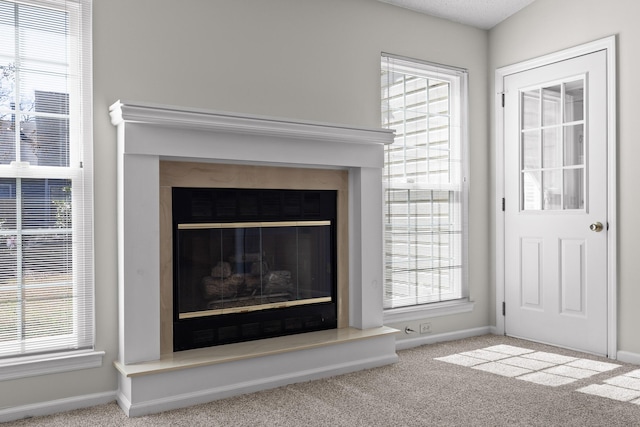 room details featuring carpet floors, a glass covered fireplace, and baseboards