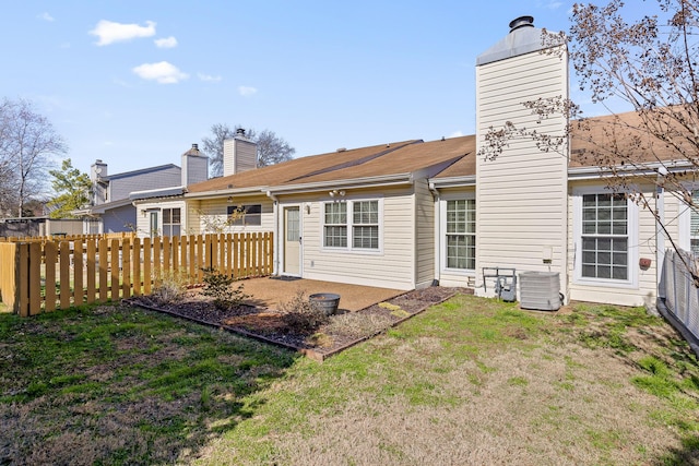 back of property with a lawn, a fenced backyard, a chimney, central air condition unit, and a patio area