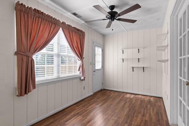 unfurnished room with dark wood-style floors, visible vents, and a ceiling fan