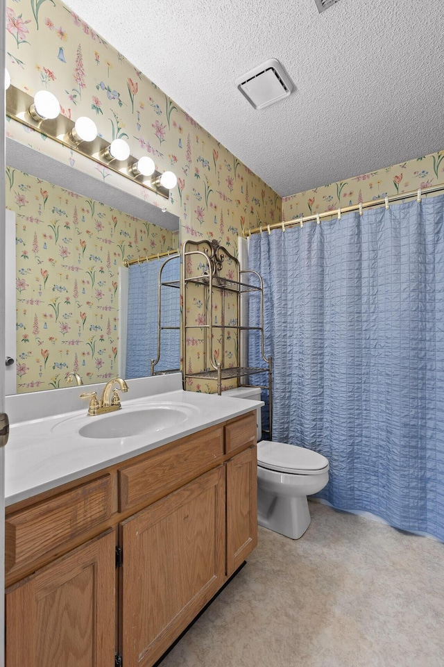 full bath with a textured ceiling, visible vents, vanity, and wallpapered walls