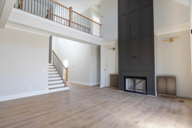 unfurnished living room with light hardwood / wood-style floors, a large fireplace, and a high ceiling