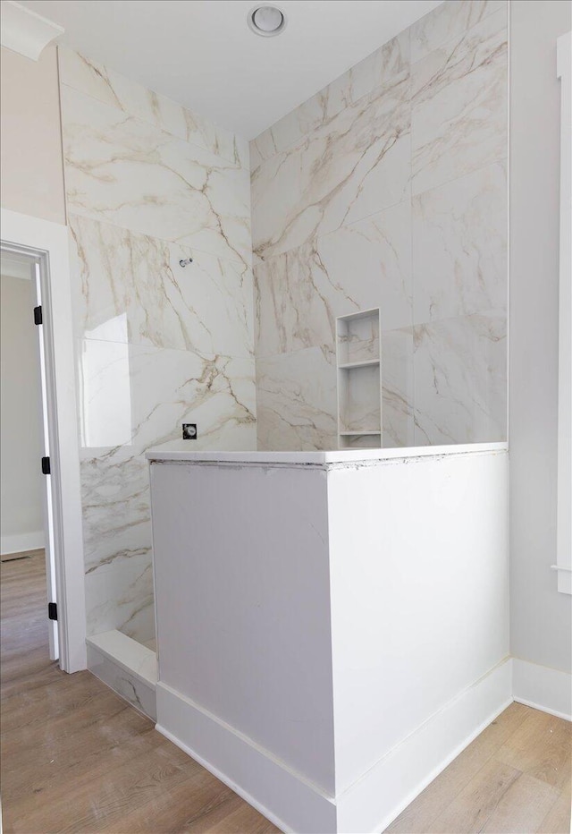 bathroom featuring hardwood / wood-style flooring and a tile shower