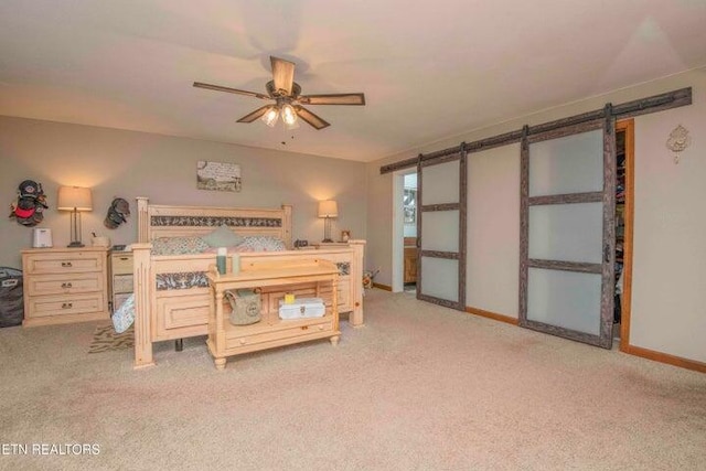 carpeted bedroom featuring ceiling fan and a barn door