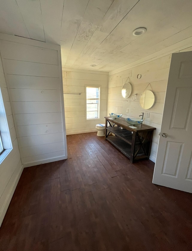 bathroom with toilet, wooden walls, vanity, and hardwood / wood-style floors