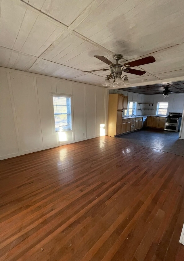 unfurnished living room featuring ceiling fan, a wealth of natural light, and dark hardwood / wood-style floors