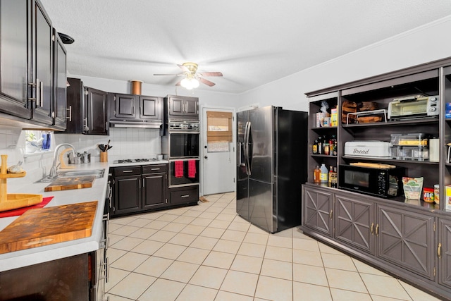 kitchen with sink, decorative backsplash, light tile patterned floors, ceiling fan, and stainless steel appliances