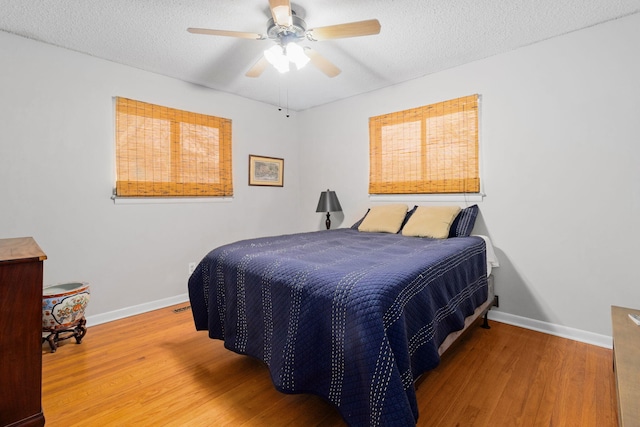 bedroom with ceiling fan, hardwood / wood-style floors, and a textured ceiling