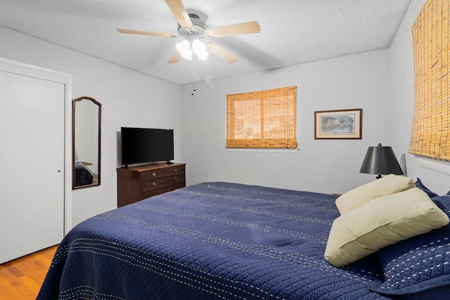 bedroom with hardwood / wood-style floors, a textured ceiling, and ceiling fan