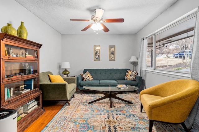 living room featuring ceiling fan, wood-type flooring, and a textured ceiling