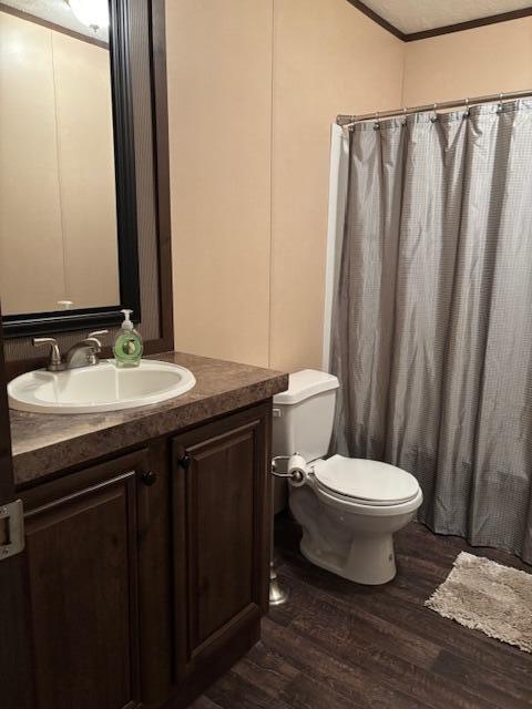 bathroom with vaulted ceiling, ornamental molding, toilet, wood-type flooring, and vanity