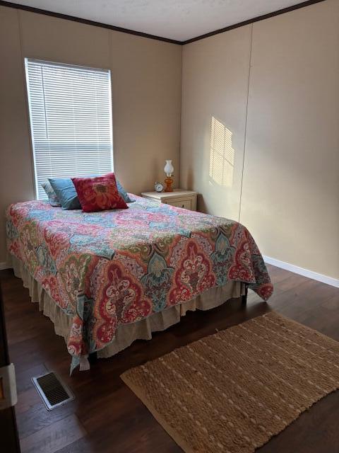 bedroom featuring dark hardwood / wood-style flooring and crown molding