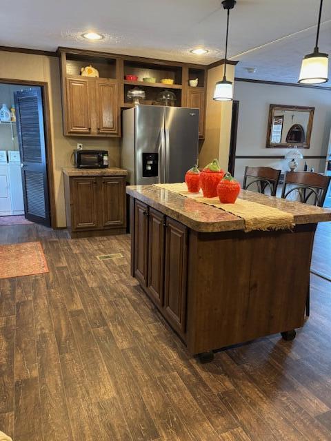 kitchen featuring a center island, pendant lighting, stainless steel refrigerator with ice dispenser, and washer and clothes dryer