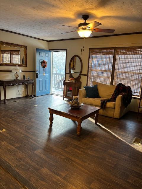 living room featuring ornamental molding, a textured ceiling, ceiling fan, and dark hardwood / wood-style floors