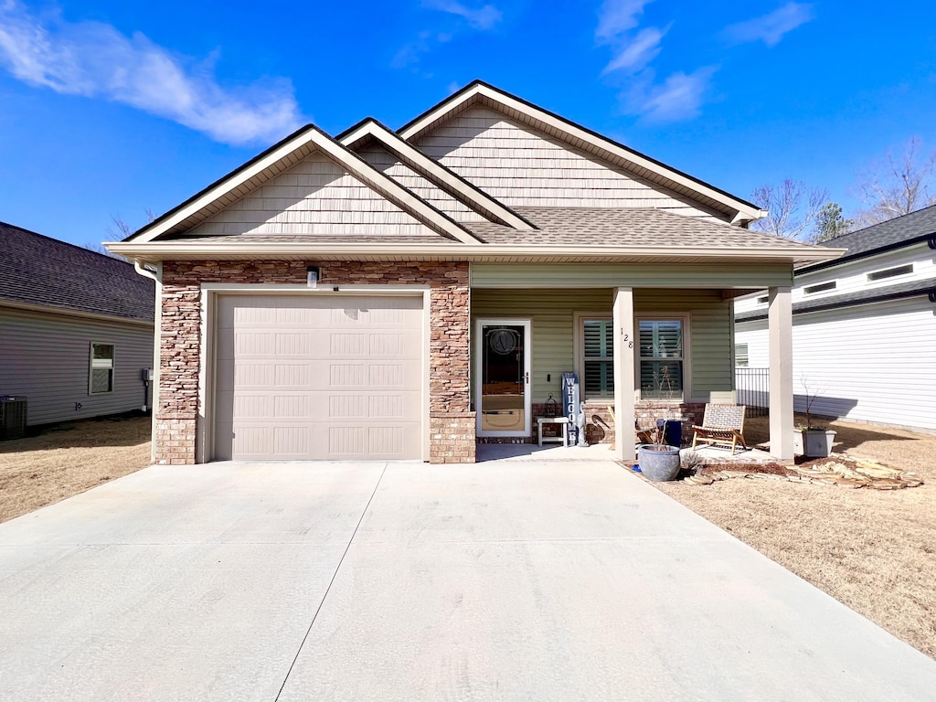 view of front of property with covered porch, central AC unit, and a garage