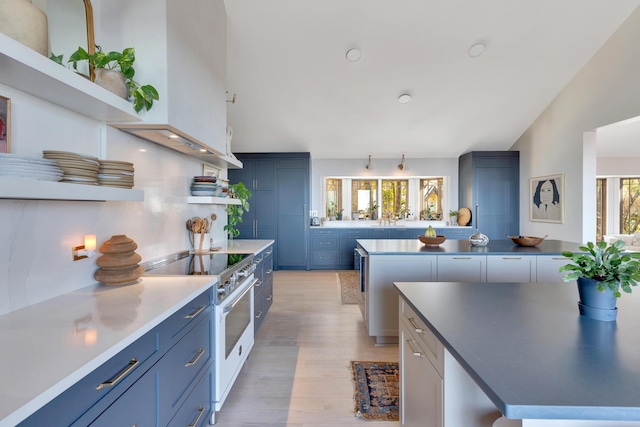 kitchen featuring blue cabinets, plenty of natural light, light wood-type flooring, and high end range