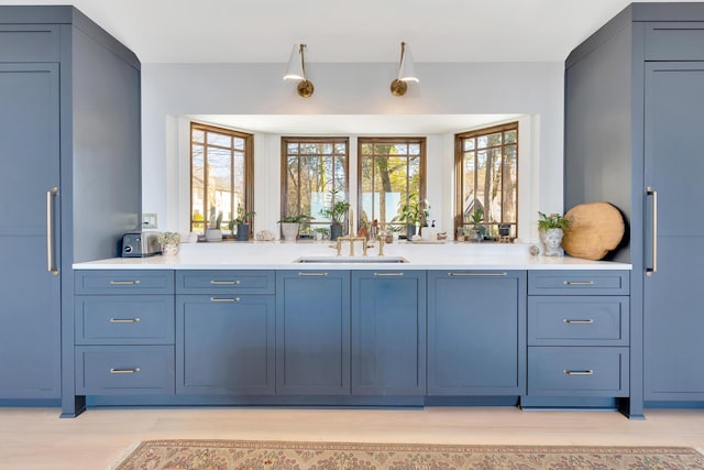 bar featuring blue cabinets, sink, and light hardwood / wood-style flooring