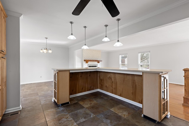 kitchen featuring a brick fireplace, crown molding, pendant lighting, and a kitchen island with sink