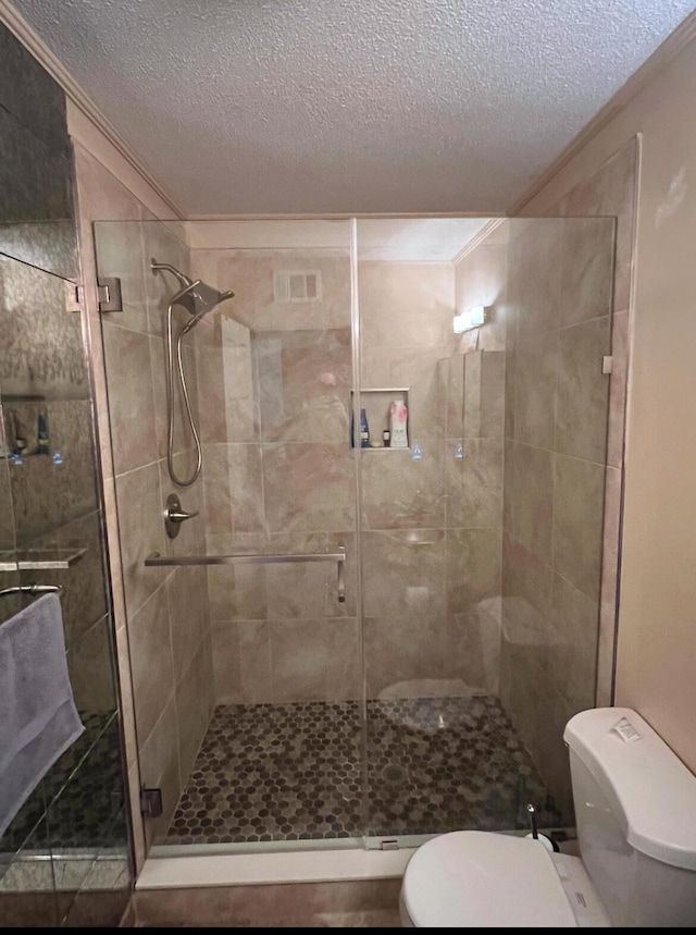 bathroom with a textured ceiling, toilet, and an enclosed shower