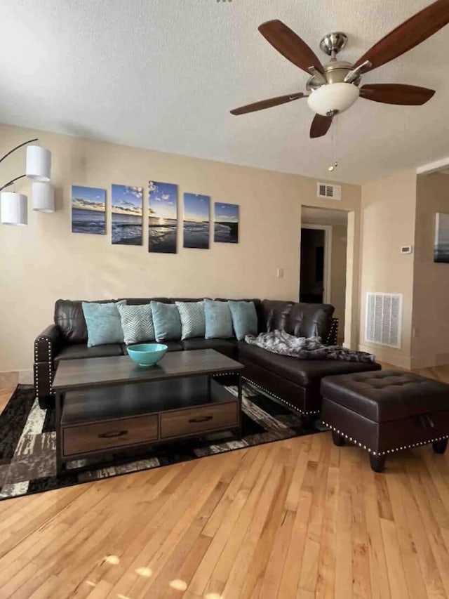 living room featuring ceiling fan, wood-type flooring, and a textured ceiling