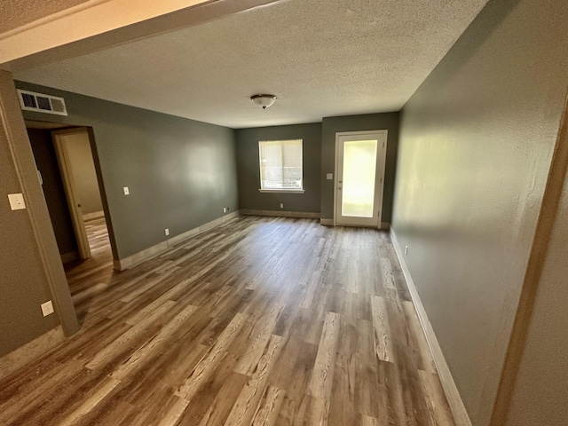 spare room with a textured ceiling and hardwood / wood-style floors