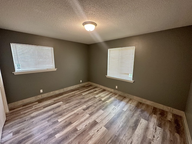 unfurnished room featuring hardwood / wood-style flooring and a textured ceiling