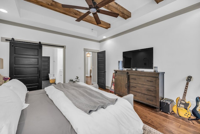 bedroom with ceiling fan, hardwood / wood-style flooring, beamed ceiling, and a barn door