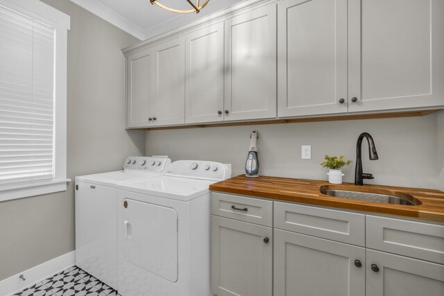 laundry room featuring sink, cabinets, washing machine and dryer, and ornamental molding