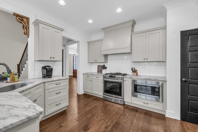 kitchen with light stone countertops, premium range hood, sink, backsplash, and stainless steel appliances