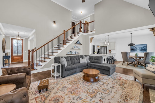 living room featuring hardwood / wood-style flooring, a high ceiling, crown molding, and a chandelier