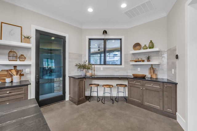 bar with dark brown cabinets, dark stone counters, and ornamental molding