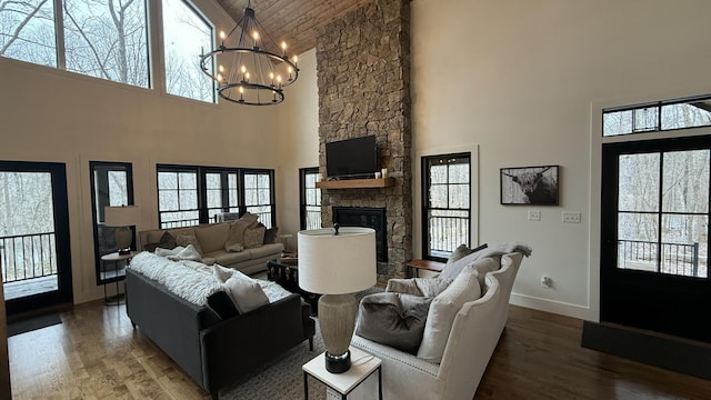 living room featuring plenty of natural light, a towering ceiling, hardwood / wood-style floors, and a stone fireplace