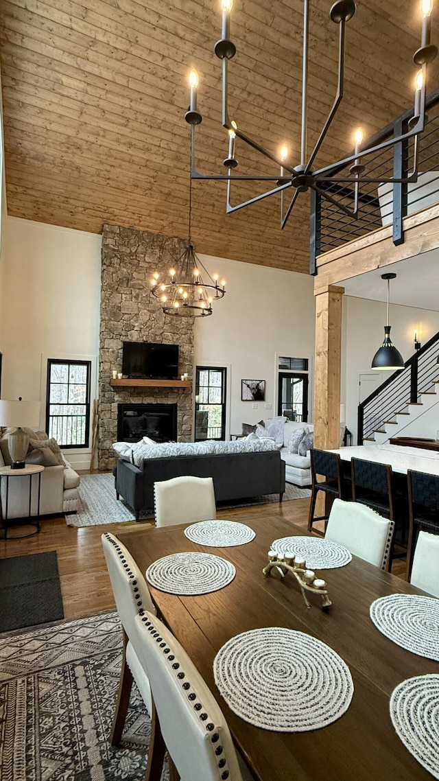 dining room featuring a notable chandelier, wooden ceiling, a fireplace, and high vaulted ceiling